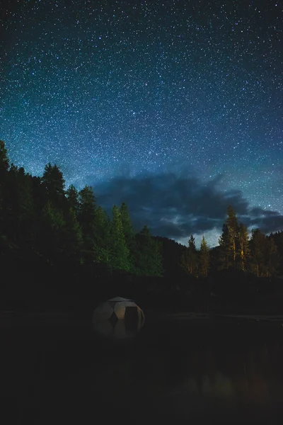 Starry night sky over small dome structure in hot spring pool. Bright night sky seen from the Dark Sky Corridor in Idaho, USA.