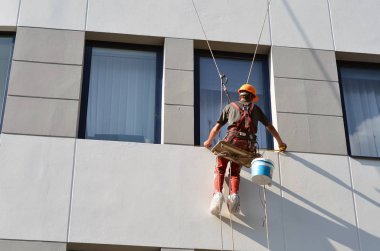İşçi cephenin ofis binasının penceresini ölçer