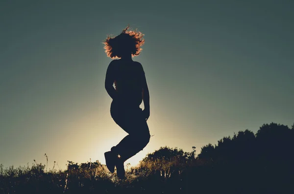 silhouette of woman in jump on background of sunset