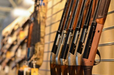 guns in row in weapons store in selective focus clipart