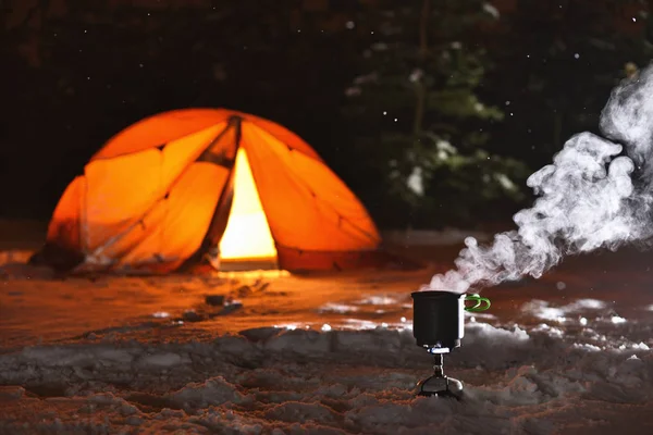 在背景帐篷和冬夜森林的露营炉上烹调食物 — 图库照片