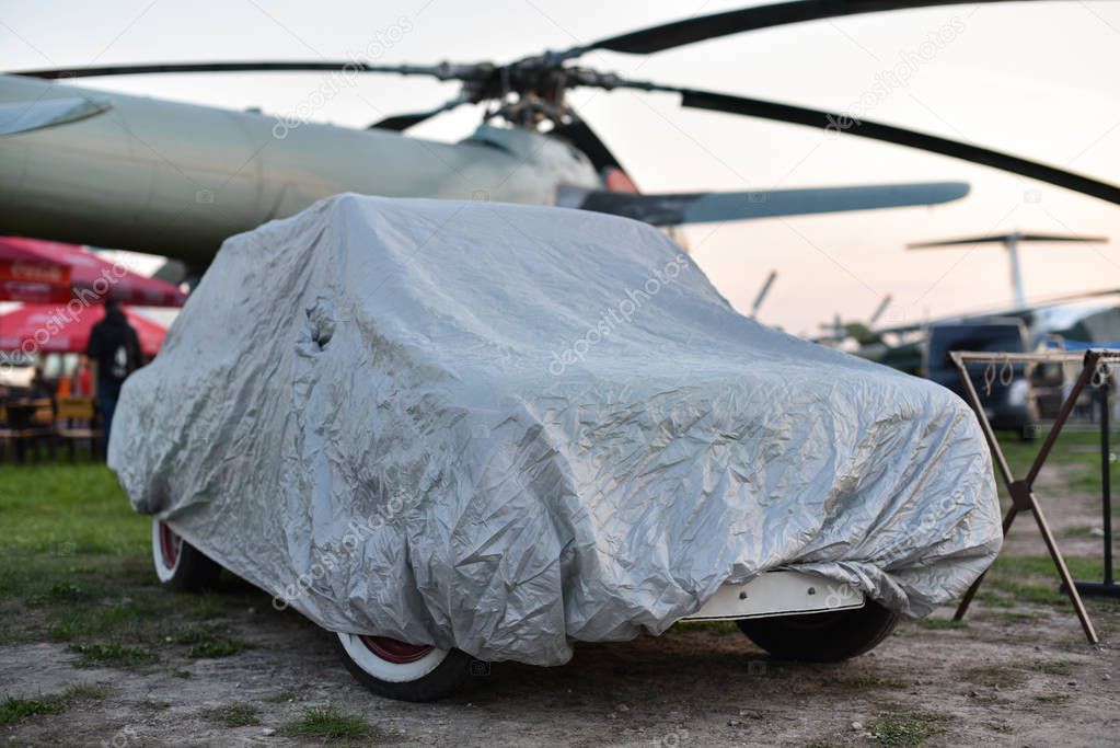 A car parked with a a protective cover on airdrome