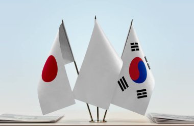 Japonya, Güney Kore ve beyaz bayraklar masada gazeteler
