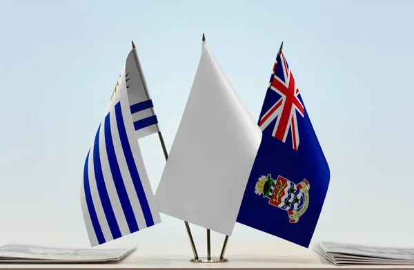 开曼群岛和乌拉圭的国旗立着 上面有文件 — 图库照片