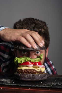 Taze pişmiş siyah burger pişiren adam.