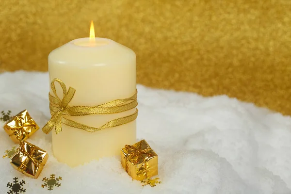 背景に雪の中で黄金のクリスマスの装飾が施されたクリスマスキャンドル — ストック写真