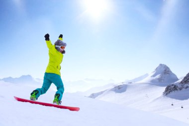 Kız snowboardcu Alp dağlarında yamaçtan aşağı koşuyor. Kış sporu ve eğlence, boş zaman aktiviteleri. Heyecanlı çığlık atan genç kadın eğlence konsepti