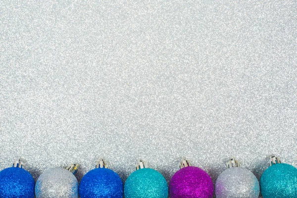 Christmas decoration of colorful glitter balls on silver glitter background with copy space for text new year card concept