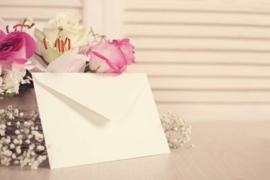 Bir sepet çiçek ve ahşap zemin üzerinde boş bir zarf.