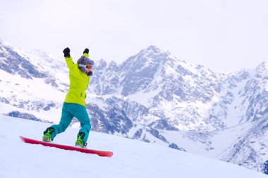 Kız snowboardcu Alp dağlarında yamaçtan aşağı koşuyor. Kış sporu ve eğlence, boş zaman aktiviteleri. Heyecanlı çığlık atan genç kadın eğlence konsepti