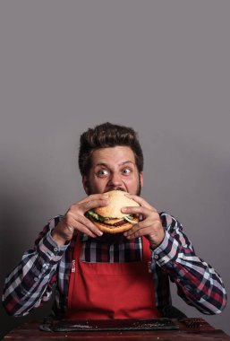 Genç adam taze hamburgeri ısırıyor.