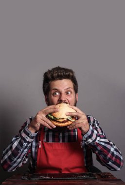 Young man biting fresh tasty hamburger clipart