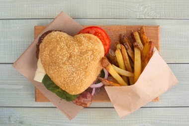 Kalp şeklinde hamburger ve patates kızartması, hamburger fast food konsepti sevgililer günü sürprizi akşam yemeği, ahşap arka plan, düz manzara