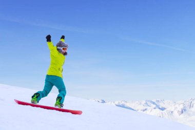 Kız snowboardcu Alp dağlarında yamaçtan aşağı koşuyor. Kış sporu ve eğlence, boş zaman aktiviteleri. Heyecanlı çığlık atan genç kadın eğlence konsepti
