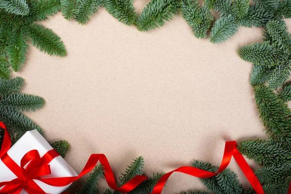 クリスマス高貴なモミの木の小枝とギフトで赤リボンで茶色の紙の背景とともにコピースペースのためのテキスト — ストック写真