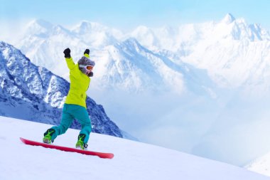 Kız snowboardcu Alp dağlarında yamaçtan aşağı koşuyor. Kış sporu ve eğlence, boş zaman aktiviteleri. Heyecanlı çığlık atan genç kadın eğlence konsepti