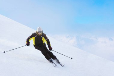Alp kayakçısı güzel Alp manzarasında yokuş aşağı koşuyor. Arka planda mavi gökyüzü. Metin için boş kopyalama alanı