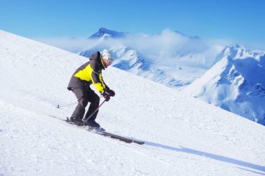 Alp devi slalom kayakçısı güzel Alp manzarasında yokuş aşağı koşuyor. Arka planda mavi gökyüzü. Metin için boş kopyalama alanı
