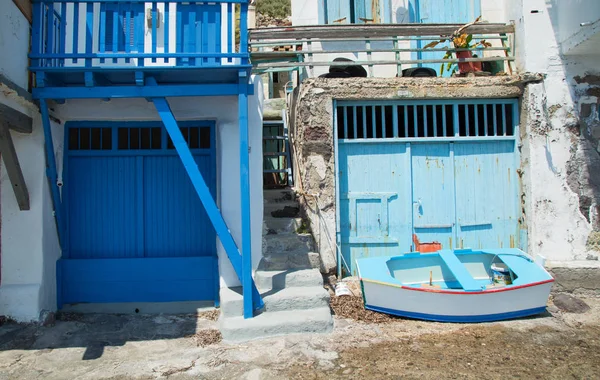 Milos Adası Yunanistan köyde Klima mavi kapılı bir evin önünde mavi balıkçı teknesi