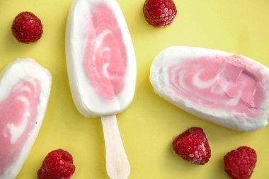 Ahududu üzerinde sarı bir arka plan ile Berry sorbe ve yoğurt popsicles