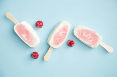 Üç meyvenin sorbe ve yoğurt ile soluk mavi arka plan üzerinde ahududu buzlu şeker