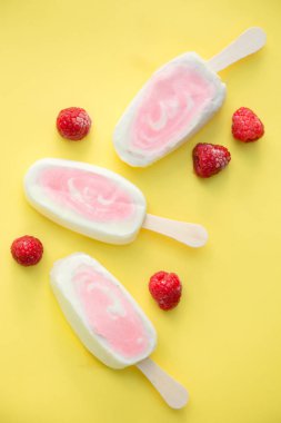 Üç meyvenin sorbe ve yoğurt ile sarı bir arka plan üzerinde ahududu buzlu şeker