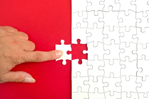 Hand holding piece of white puzzle on blue background. Business and team work concept