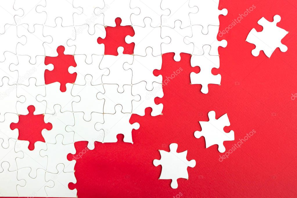 Unfinished white puzzle on a red background