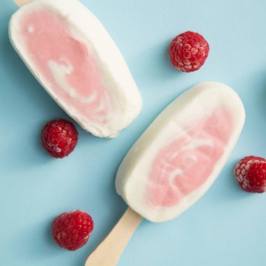 İki meyvenin sorbe ve yoğurt ile soluk mavi arka plan üzerinde ahududu buzlu şeker