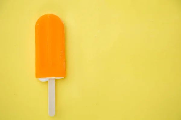 Oranje Popsicle Een Gele Achtergrond — Stockfoto