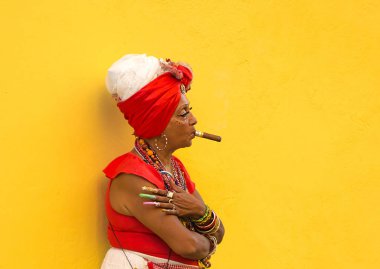 Havana-Küba-Aralık 4, 2018: Kadın sarı arka plan izin turistler ile onun ağzına bir puro Havana Küba sokakta birkaç peso için onu fotoğraf çekmek. Bir Küba geleneği.