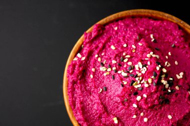 Üst görünüm ve siyah arka planda kaşıkla renkli pancar pancarı humusunu kapat 