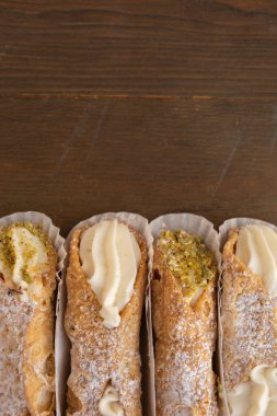 Dört Cannoli 'nin en üst görüntüsü Ahşap bir arka planda güzel bir kağıtta yeni sergileniyor