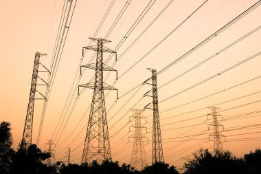Gökyüzü günbatımı arka planında yüksek voltaj direği.