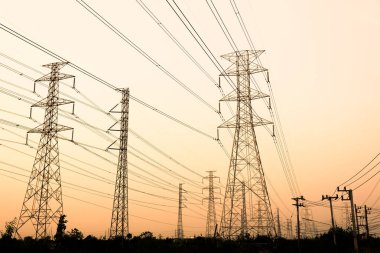 Gökyüzü günbatımı arka planında yüksek voltaj direği.