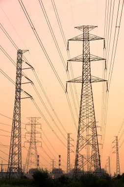 Gökyüzü günbatımı arka planında yüksek voltaj direği.