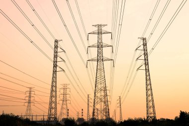 Gökyüzü günbatımı arka planında yüksek voltaj direği.