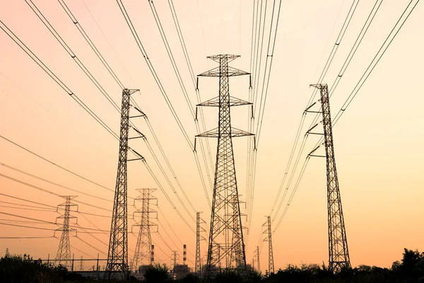 Gökyüzü günbatımı arka planında yüksek voltaj direği.