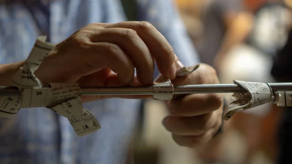Tokyo, Japonya - Ağustos 2018: Kimliği belirsiz bir adamın ellerini Omikuji ile düğümleyerek kapatın - Paper Fortune gece Sensoji Asakusa Kannon Tapınağı'nda