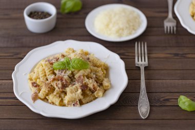 Ev yapımı makarna carbonara İtalyanca ile pastırma, yumurta, karanlık bir arka plan üzerinde beyaz tabakta Parmesan peyniri.