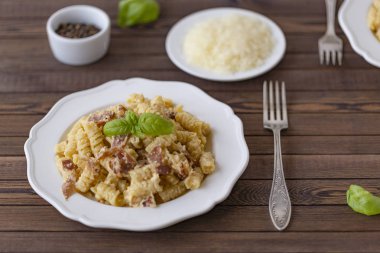 Ev yapımı makarna carbonara İtalyanca ile pastırma, yumurta, karanlık bir arka plan üzerinde beyaz tabakta Parmesan peyniri.
