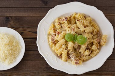 Ev yapımı makarna carbonara İtalyanca ile pastırma, yumurta, karanlık bir arka plan üzerinde beyaz tabakta Parmesan peyniri.