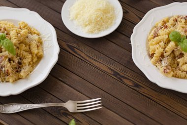 Ev yapımı makarna carbonara İtalyanca ile pastırma, yumurta, karanlık bir arka plan üzerinde beyaz tabakta Parmesan peyniri.