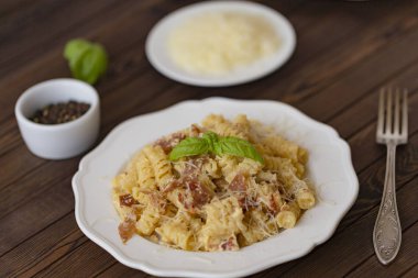 Ev yapımı makarna carbonara İtalyanca ile pastırma, yumurta, karanlık bir arka plan üzerinde beyaz tabakta Parmesan peyniri.
