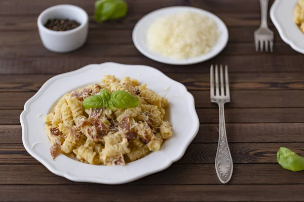 Ev yapımı makarna carbonara İtalyanca ile pastırma, yumurta, karanlık bir arka plan üzerinde beyaz tabakta Parmesan peyniri.