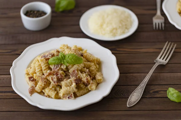 Ev yapımı makarna carbonara İtalyanca ile pastırma, yumurta, karanlık bir arka plan üzerinde beyaz tabakta Parmesan peyniri.