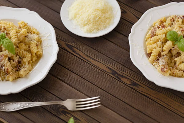 Ev yapımı makarna carbonara İtalyanca ile pastırma, yumurta, karanlık bir arka plan üzerinde beyaz tabakta Parmesan peyniri.