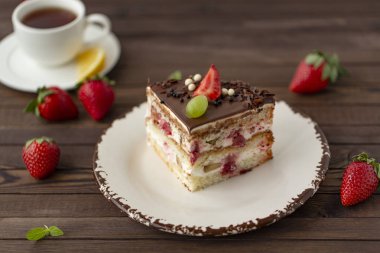 Kek çilek, üzüm ve çikolata. Koyu ahşap arka plan üzerinde.