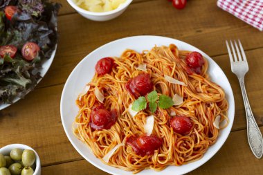 ahşap masa üzerinde tabak domates soslu spagetti