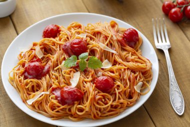 ahşap masa üzerinde tabak domates soslu spagetti